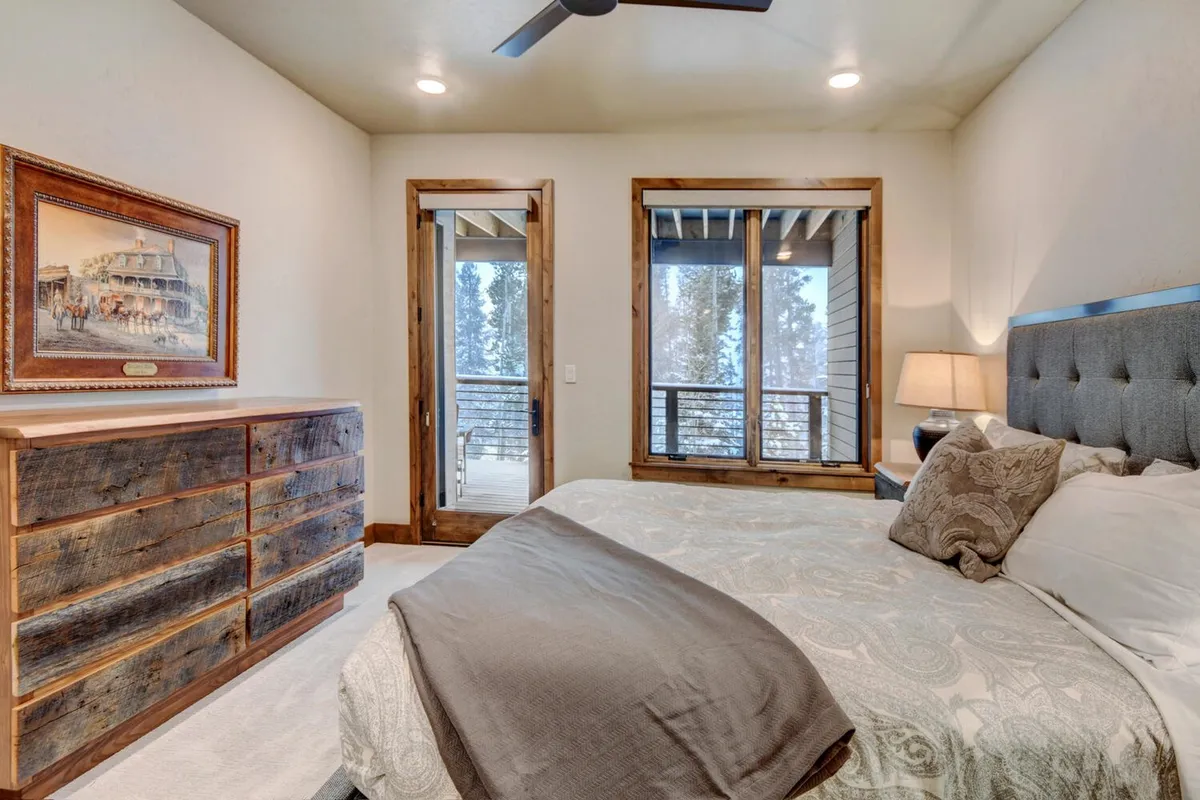A tranquil bedroom featuring a plush bed, a wooden dresser, and large windows letting in abundant natural light. The scene is calm, inviting, and highlights the restful ambiance of the sleeping quarters.